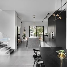 an open kitchen and dining area with black counter tops, white walls, and stairs