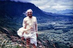 an old man standing on top of a grass covered hill