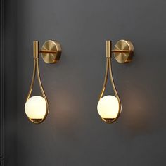 two wall lights that are next to each other on a gray wall in a room