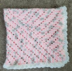 a pink and white crocheted blanket laying on the floor