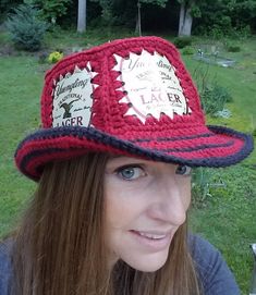 a woman wearing a red and black crocheted hat with labels on the brim