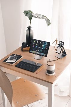 a wooden table topped with a laptop computer next to a phone and other items on top of it