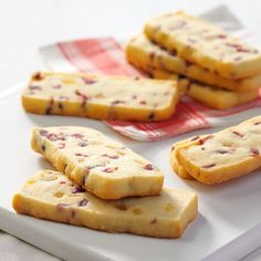 some cookies are on a white plate and one is cut in half to look like it has cranberry toppings