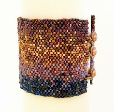 a close up of a bracelet on a white pillar with beads and chains attached to it