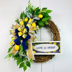 a wreath with yellow and blue decorations is hanging on the wall next to a sign