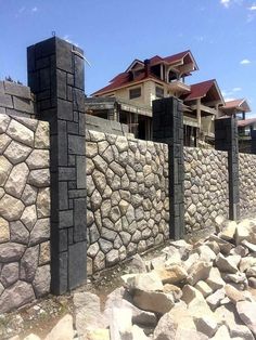 a stone wall and some rocks in front of a house