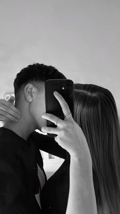 a woman taking a selfie with her cell phone while she is wearing a black shirt and tie