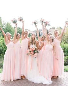 a group of bridesmaids in pink dresses holding bouquets and posing for the camera