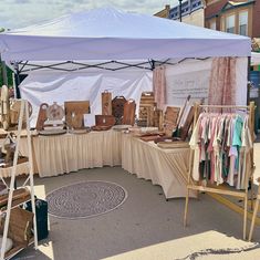 an outdoor market with clothes on display under a tent