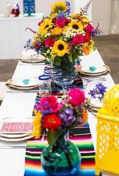 a table set with colorful flowers and place settings