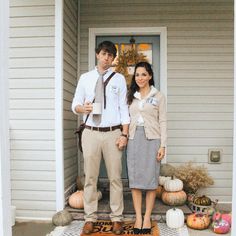 a man and woman standing in front of a house with pumpkins on the porch