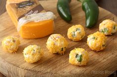 several cheese balls on a cutting board next to green peppers