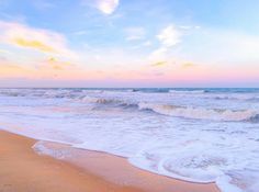 an ocean beach with waves coming in to shore and the sun going down over the horizon