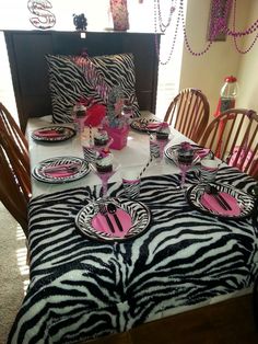 a zebra print table cloth with pink and black plates on it, along with place settings