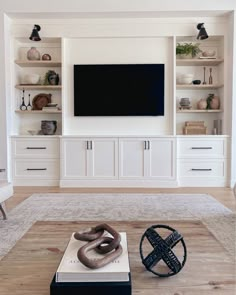 a living room with white built in cabinets and a flat screen tv