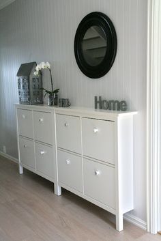 there is a white dresser with drawers and a mirror on the wall next to it