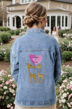 a woman wearing a jean jacket with two giraffes and a heart on it