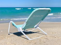 a blue lawn chair sitting on top of a sandy beach