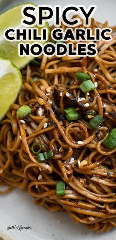 spicy chili garlic noodles on a plate with lime wedges