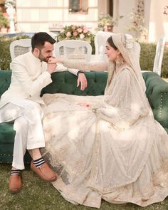 a bride and groom sitting on a green couch