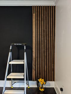 a ladder is next to a black wall with wooden slats