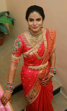 a woman in a red and gold sari posing for the camera with her hands on her hips