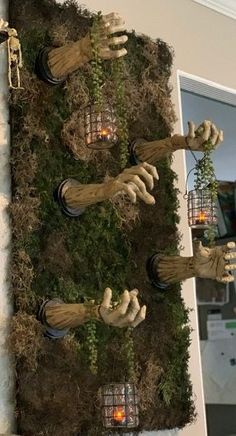 halloween decorations made out of fake hands hanging from a wall with candles and plants in them