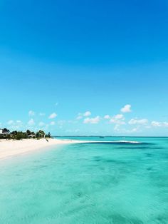 the water is crystal blue and clear with white sand on the beach in front of it