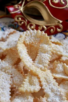 powdered sugar cookies are on a plate next to a red masquerade mask