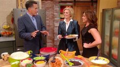 three people standing around a table full of food