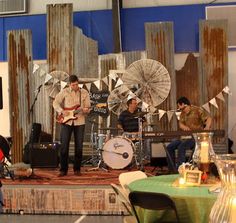 two men are playing music on stage with fans in the background and people sitting at tables