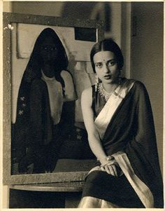 an old photo of a woman sitting in front of a mirror