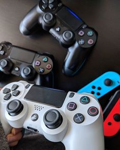 two video game controllers sitting next to each other on top of a table with remotes