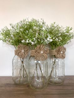 three mason jars with flowers in them sitting on a table