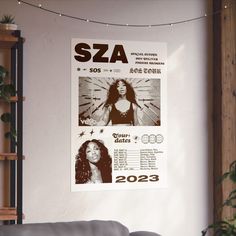 a concert poster hanging on the wall next to a couch in a room with white walls