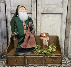 an old fashioned doll sitting on top of a wooden box next to a lit candle