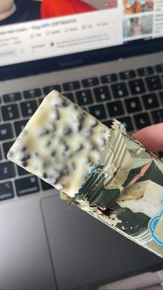 someone holding up a piece of food in front of a laptop