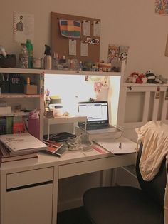 a desk with a laptop computer on top of it next to a book shelf filled with books