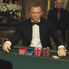 a man in a tuxedo sitting at a table with cards and poker chips