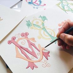 someone is drawing letters on paper with colored ink and watercolor pencils in front of them