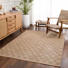 a living room area with a rug, chair and sideboard