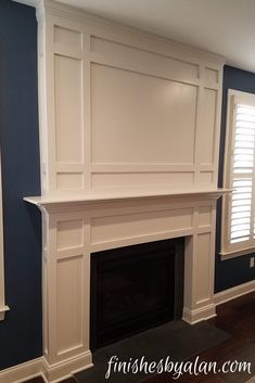 an empty fireplace in a room with blue walls and white trim on the mantel