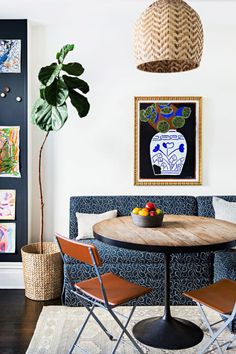 a dining room table with chairs and a potted plant in the corner next to it