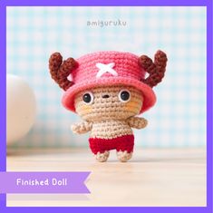 a small crocheted doll is wearing a red hat and shorts with horns on it's head