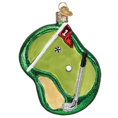 a christmas ornament with a golf ball and tee on the green field in front of a white background