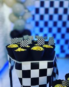 black and white checkered cupcakes with yellow frosting in them on a table