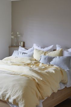 an unmade bed with white linens and yellow sheets in a neutral bedroom setting