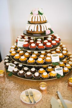 a three tiered cake with cupcakes on the top and other pastries below