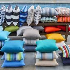 many pillows are stacked on a bench by the pool