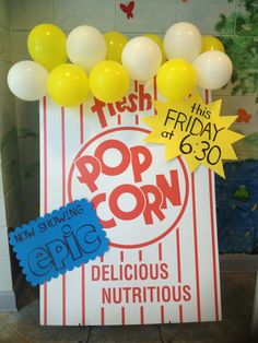 a pop corn sign surrounded by balloons and confetti